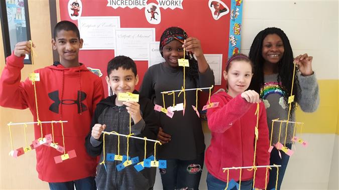 5 Elem students hold math mobiles 